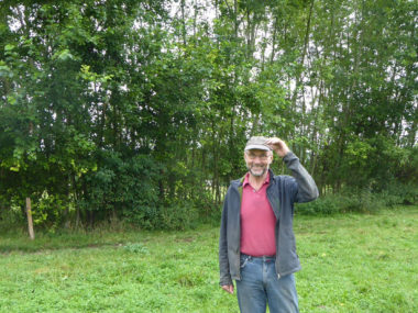Agroforst-Pionier Josef Braun steht in seinem Agroforst-System: eine Weide mit Hecken aus Bäumen und Büschen
