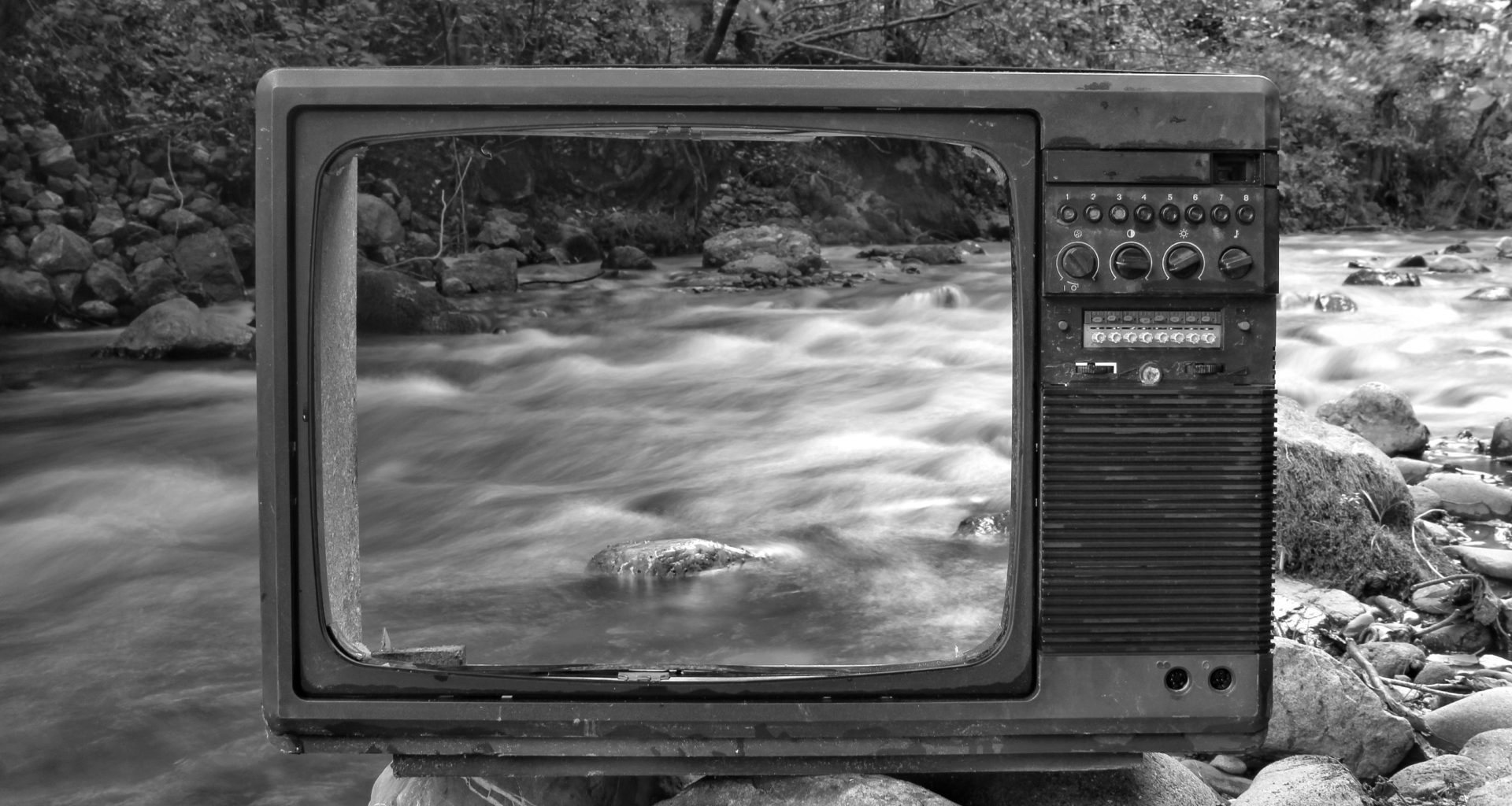 Fernseher ohne Glas vor verschwommenem Gewässer mit starker Strömung in schwarz weiß