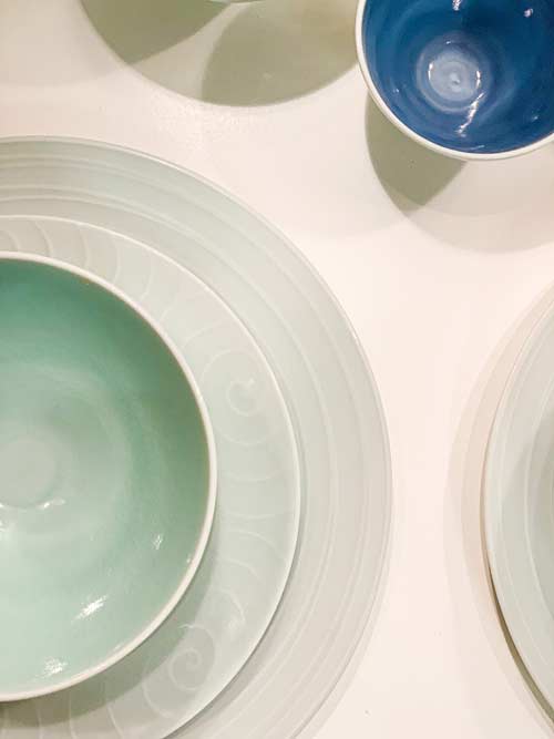 Blaue Porzellan-Teller und -Schalen stehen auf einem weißen Untergrund.
